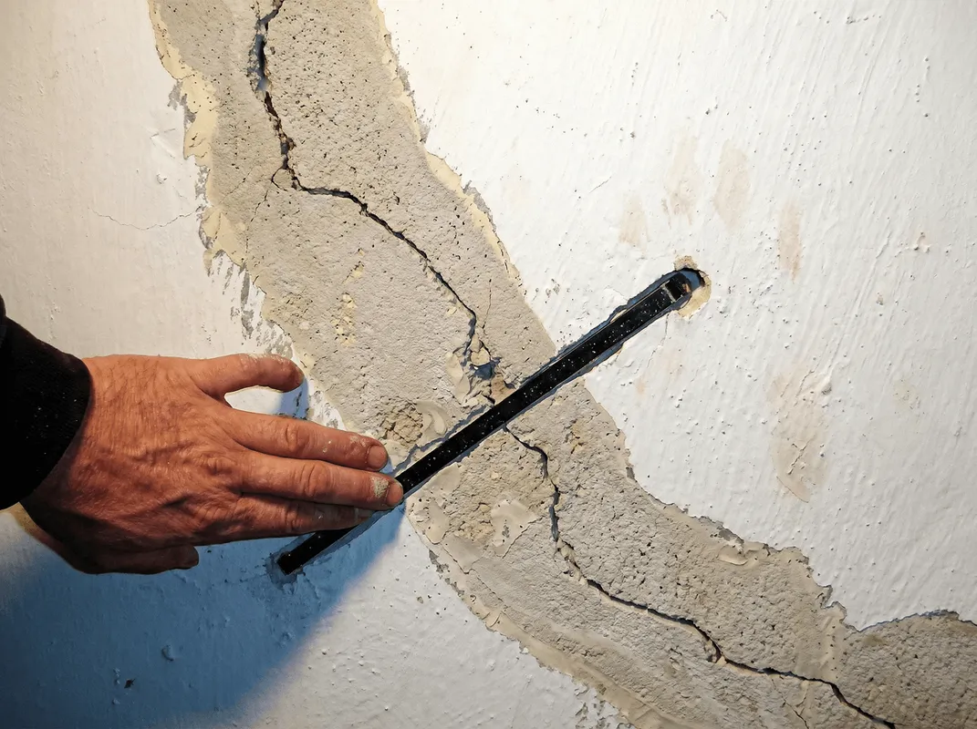 A wall with a large crack is being inspected by a professional in Erie, PA